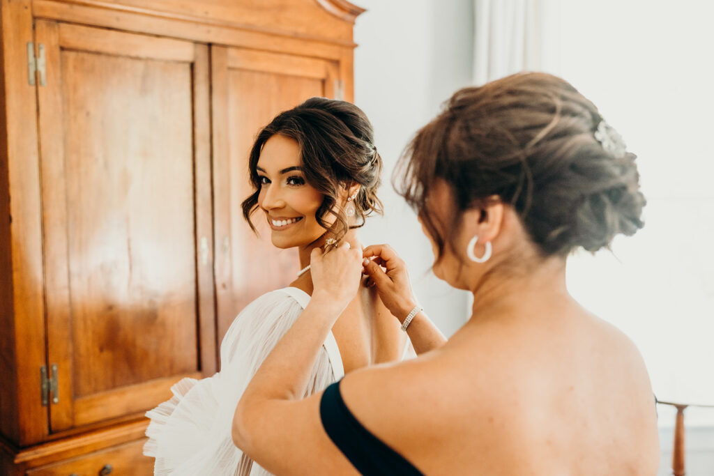 bride's mom helping her fasten her dress at rose hill estate's bridal suite