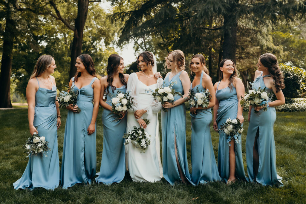 bride and bridesmaids dressed in light blue dresses laughing together outside of rose hill estate