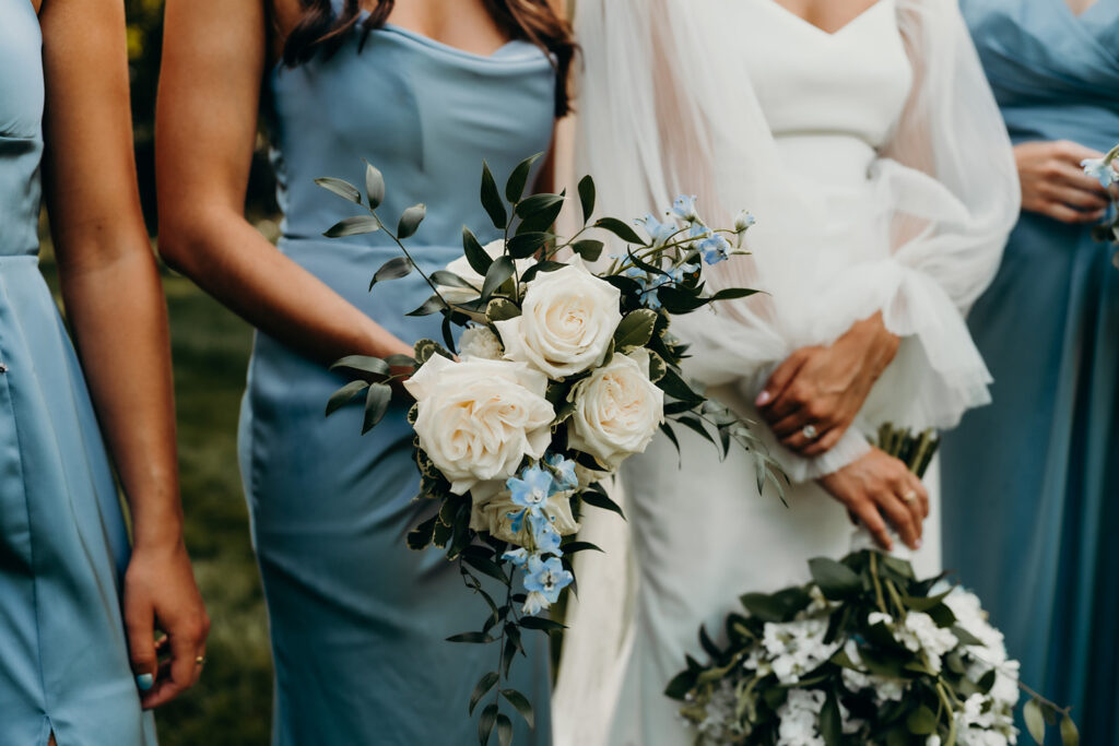 bride and bridesmaids dressed in light blue dresses laughing together outside of rose hill estate