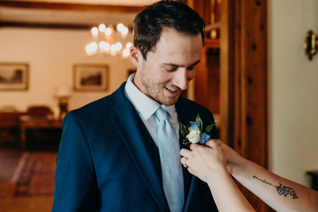 groom getting ready at rose hill estate having boutonnière put on