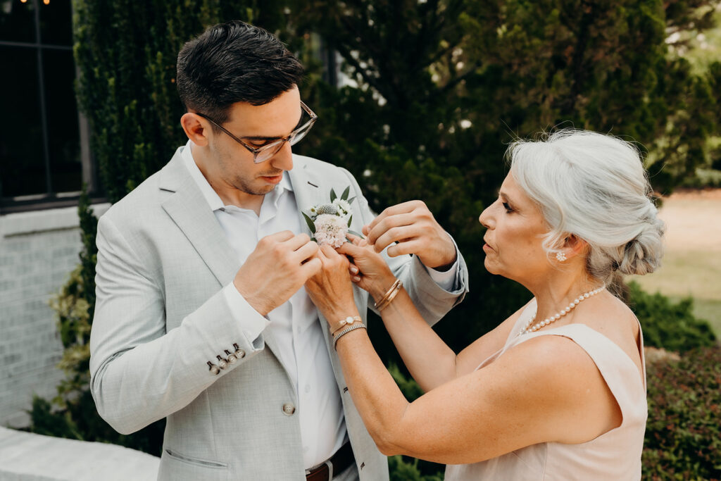 mom pinning flowers on groom