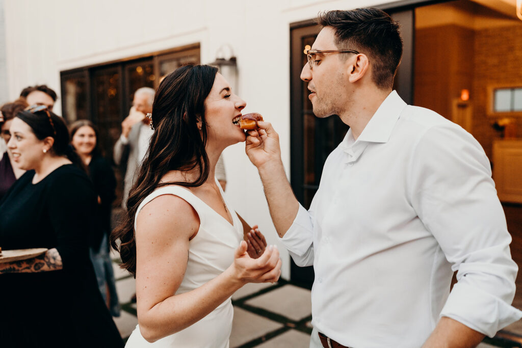 bride and groom feeding each other donuts