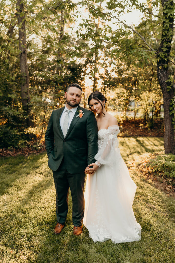 couple holding each other in front of the woods at golden hour