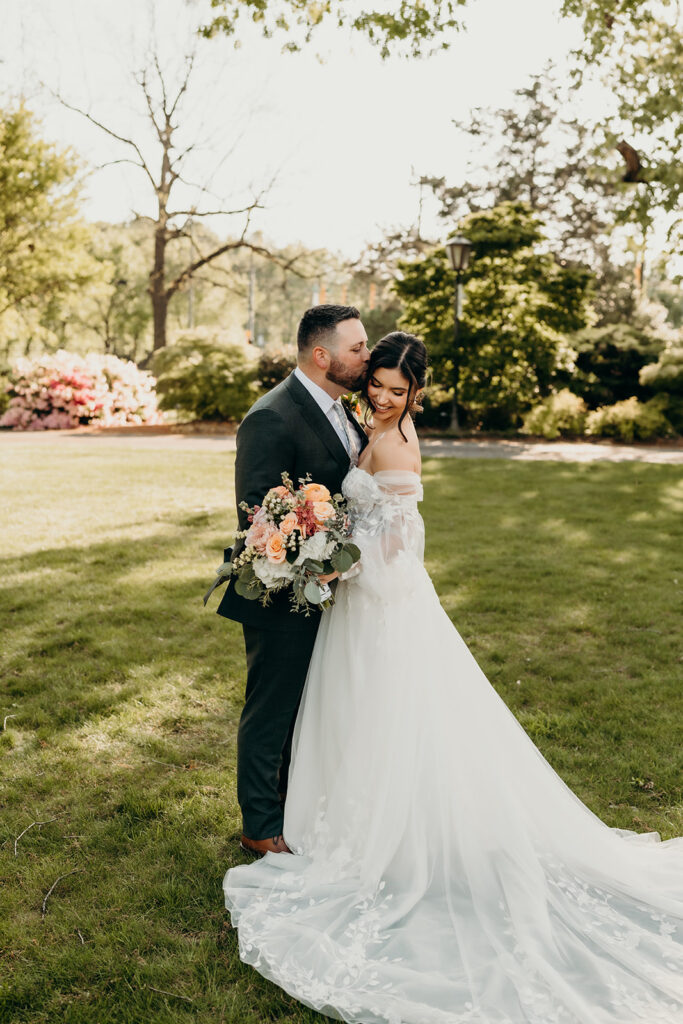 couple's portraits in the front lawn groom giving the bride a kiss on the cheek