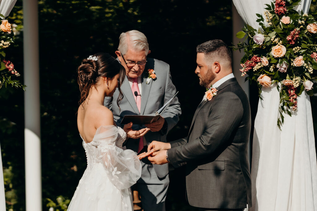 bride and groom during their ceremony exchanging rings