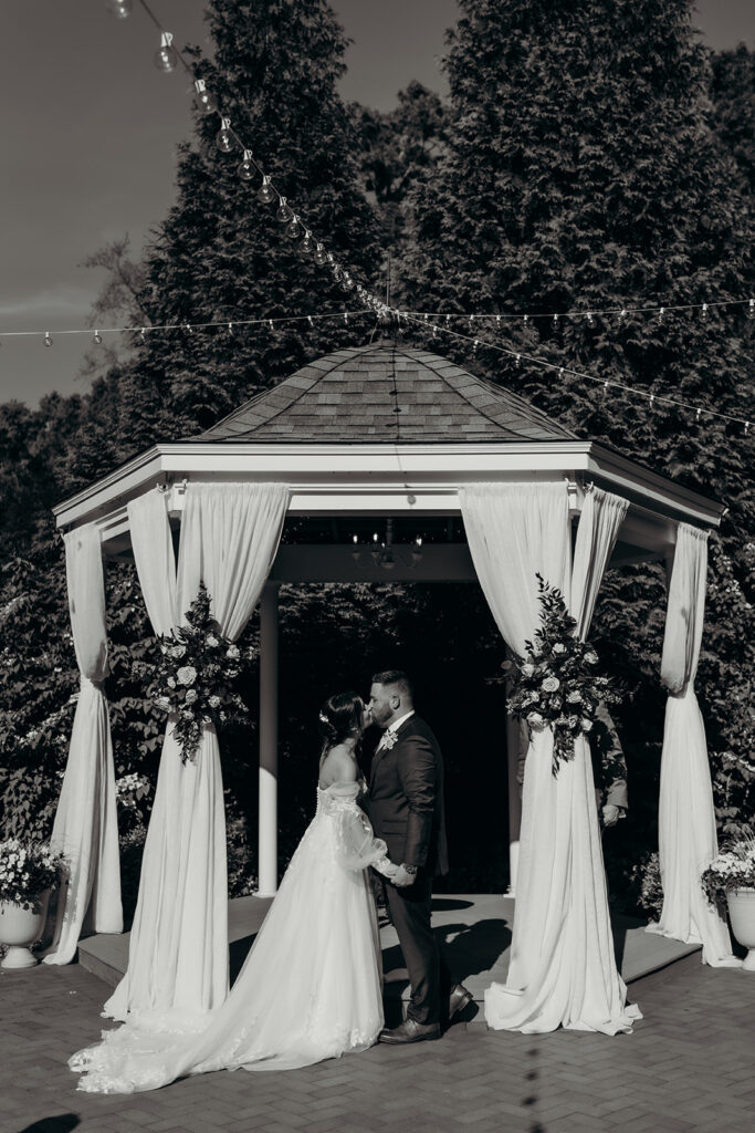 bride and groom during their ceremony first kiss at gazebo