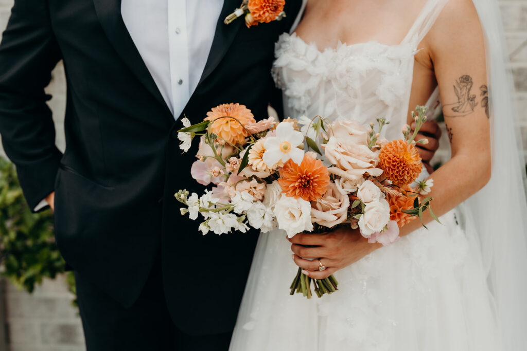 Couple holding flowers showing wedding outfits