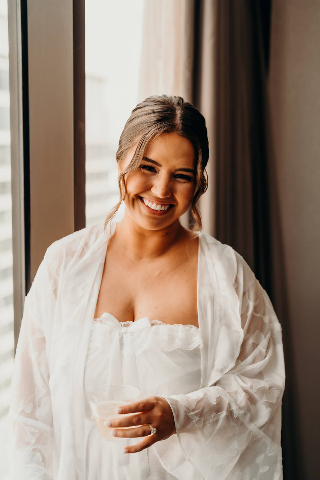 bride smiling near window while getting ready