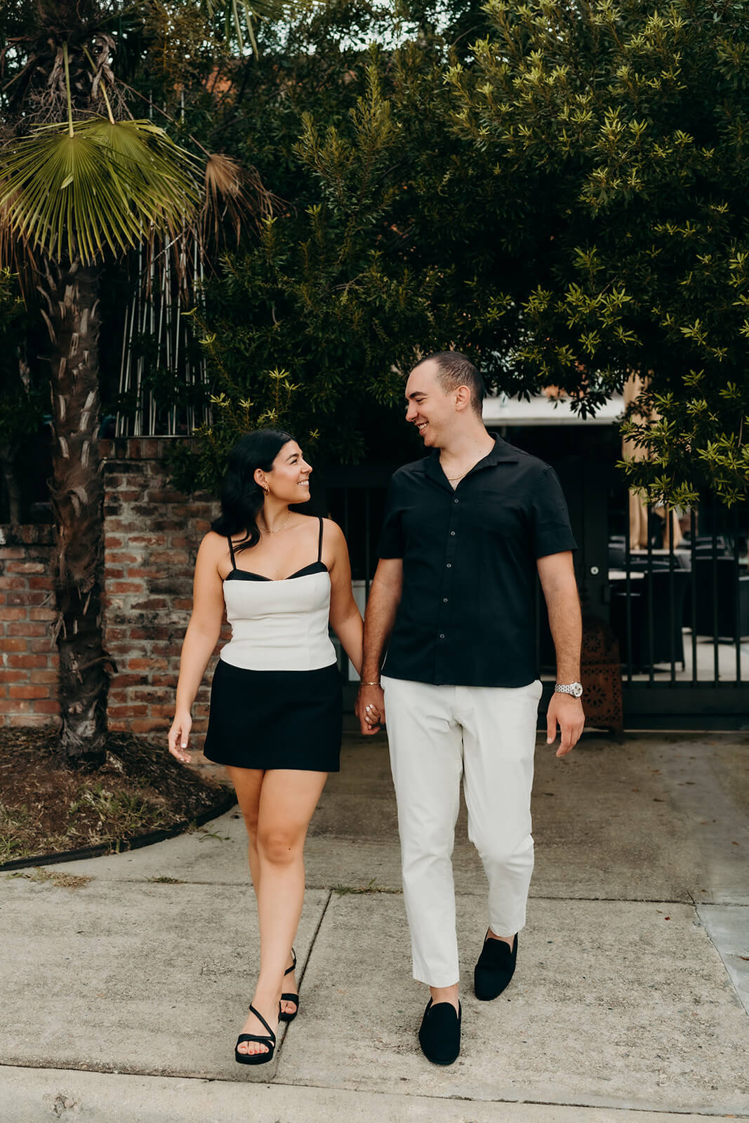 Couple walking in front of the gate during their Melrose Knitting Mill Engagement Session