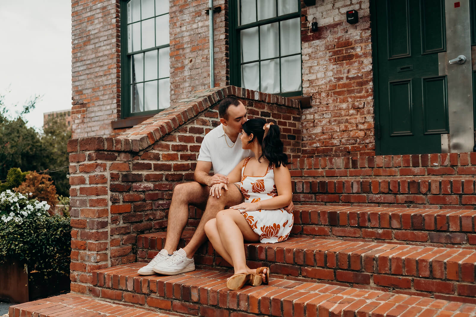 couple sitting on the brick stairs during their Melrose Knitting Mill Engagement Session