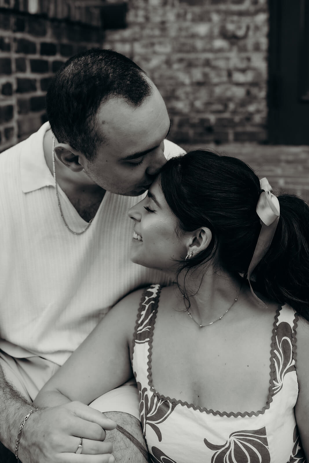 black and white photo where he is kissing her forehead and she is smiling