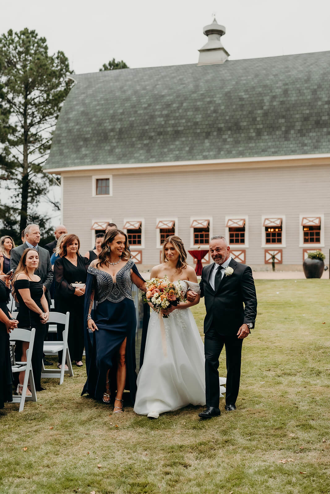 bride walking down the aisle with both of her parents at The Historic Wakefield Barn