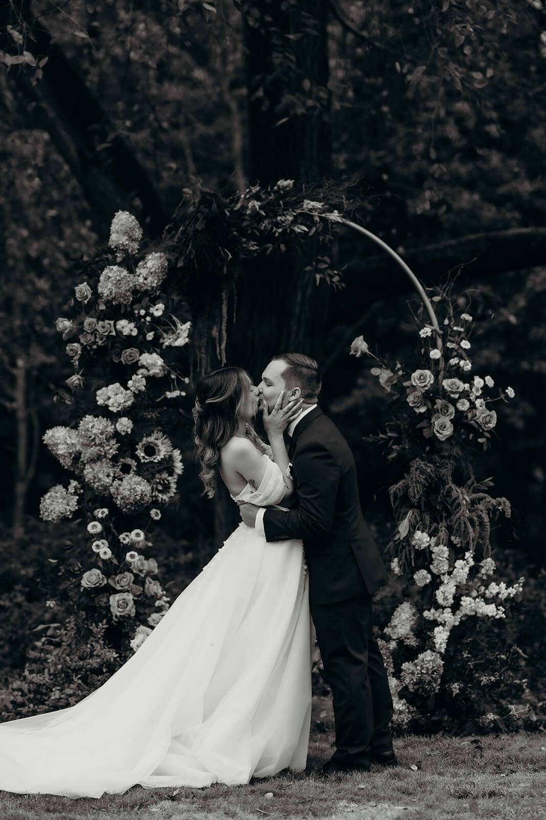 black and white photo of bride and groom sharing their first kiss