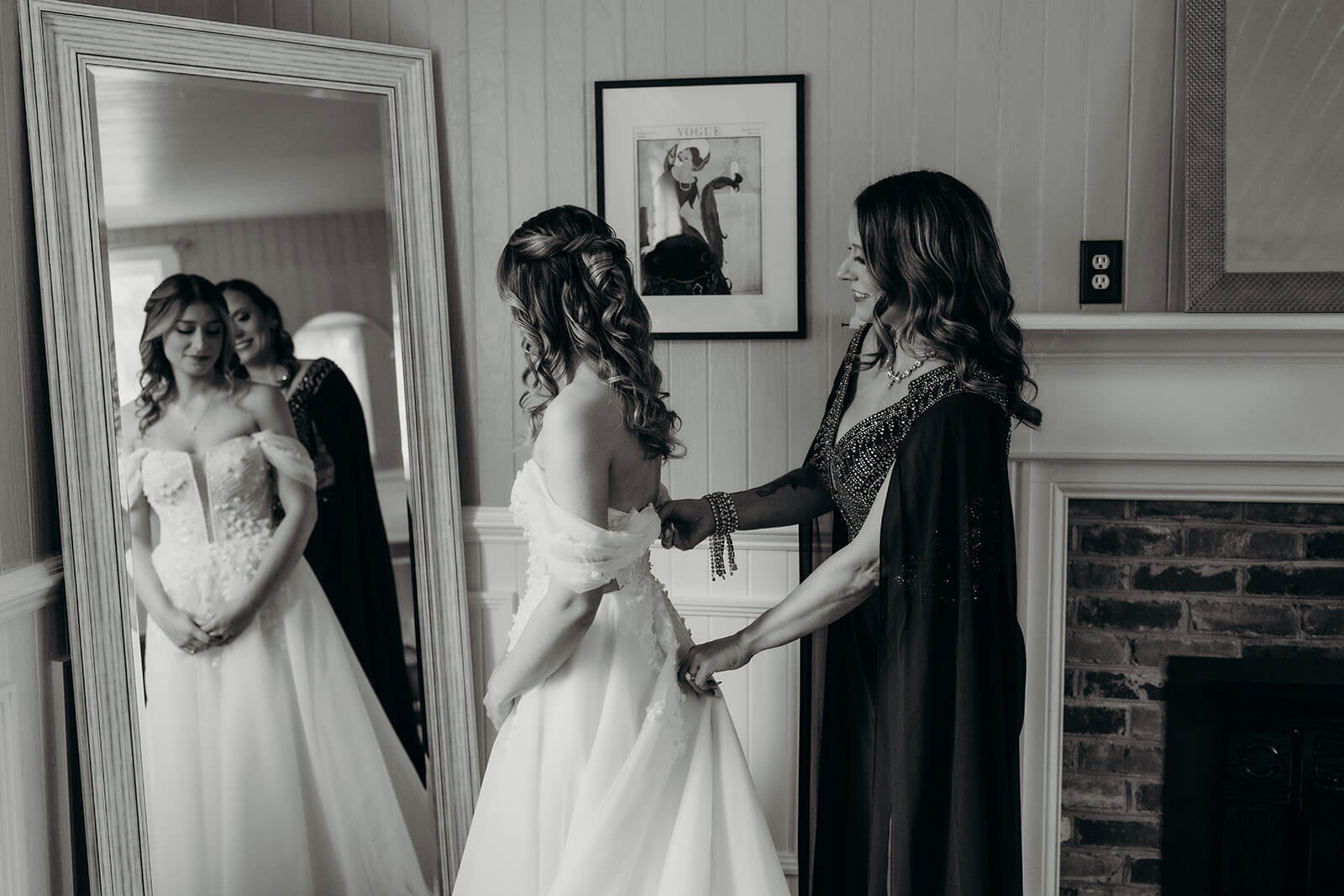 bride's mom helping her get ready in her dress