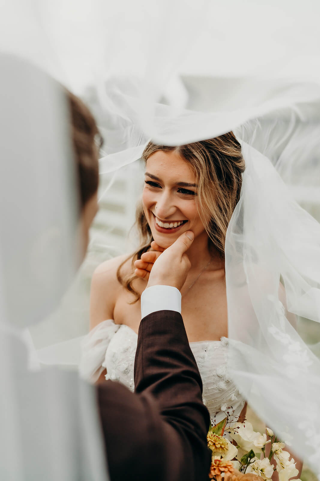 groom holding bride's face as they smile at each other
