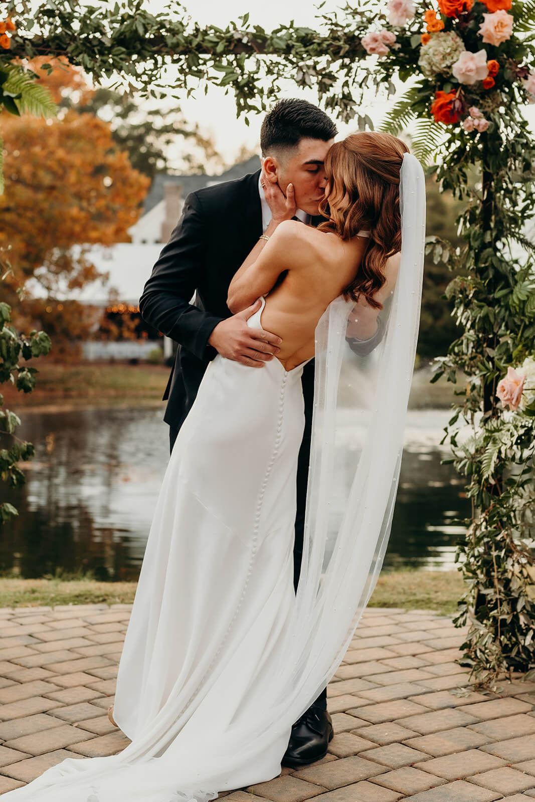 bride and groom first kiss in front of the pond at The Oaks at Salem