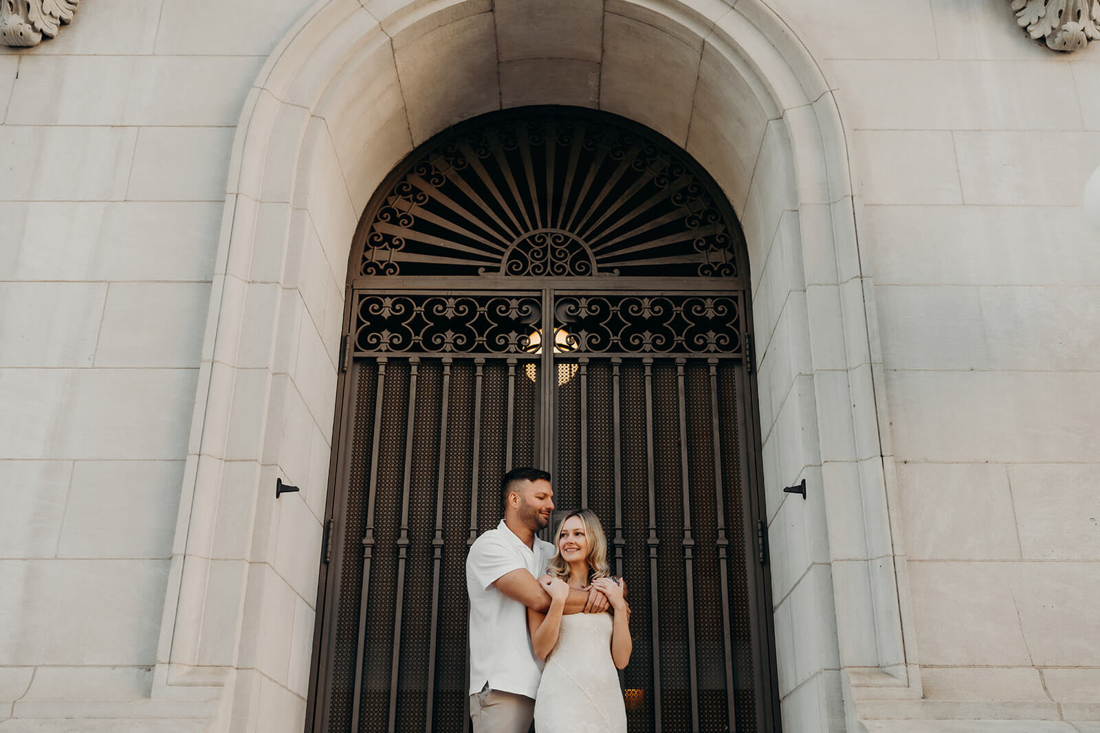couple posing romantically in front of a gated arch doorway during their downtown raleigh engagement photos
