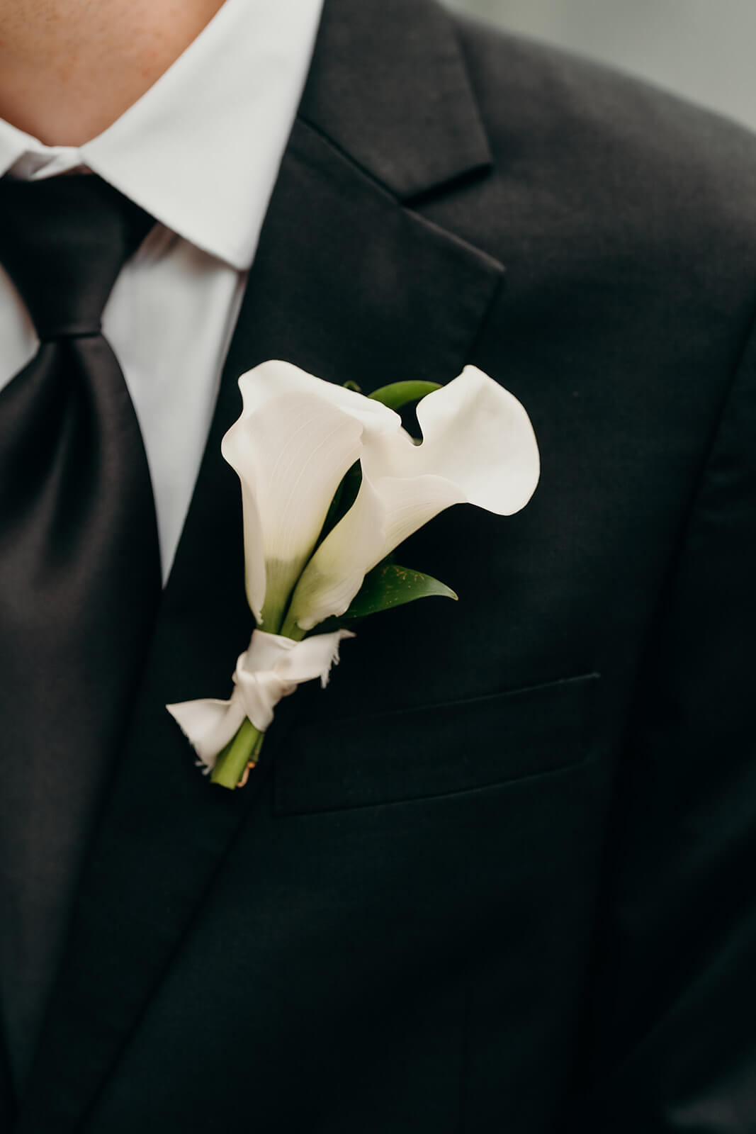 Up close photo of grooms simple white flower on lapel