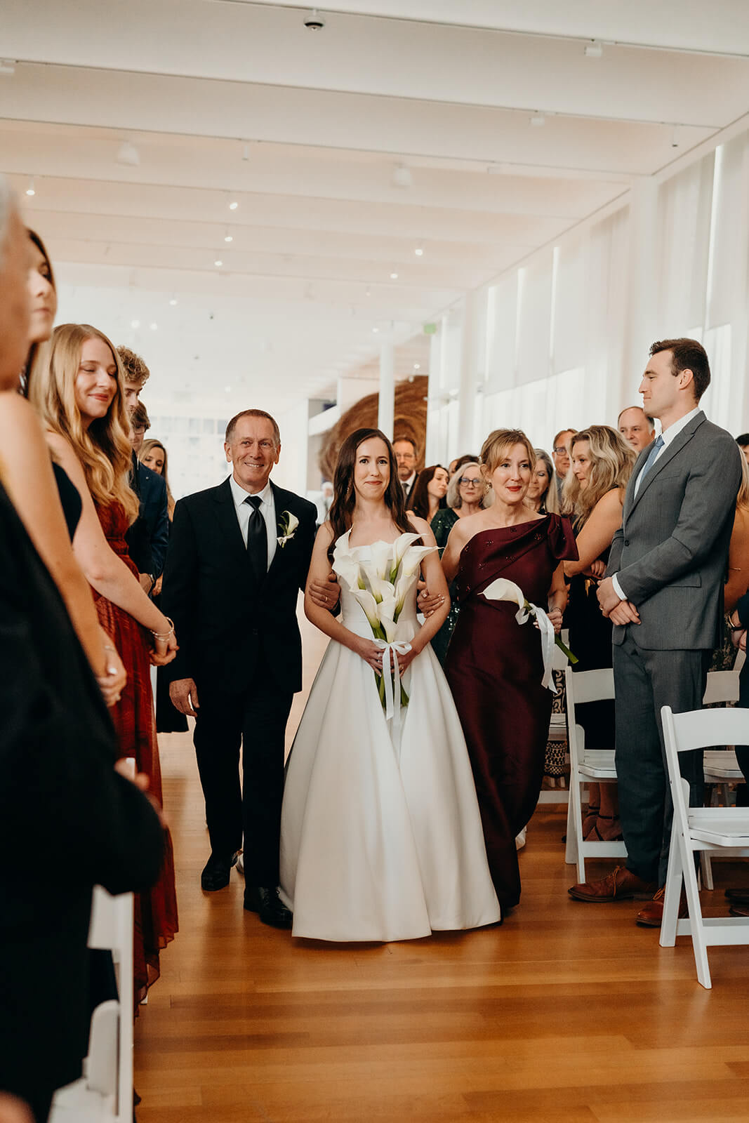 NCMA Wedding Photos of bride walking down the aisle with her parents about to be given away