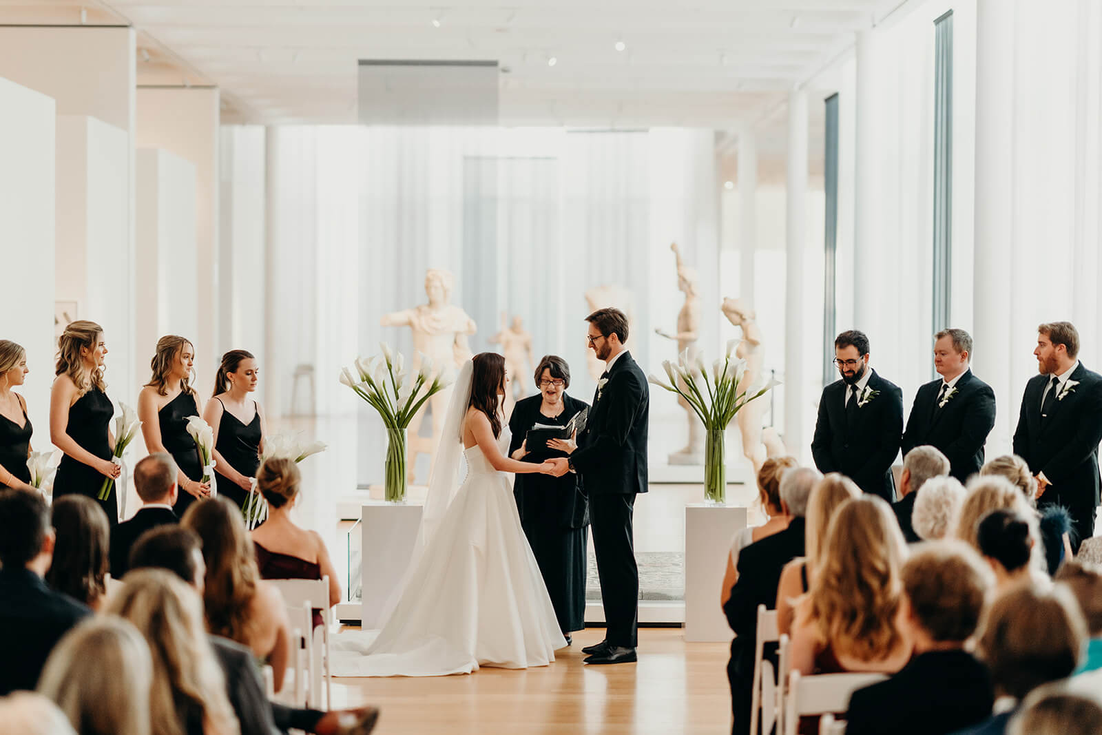 NCMA Wedding Photos of ceremony with bride and groom holding hands