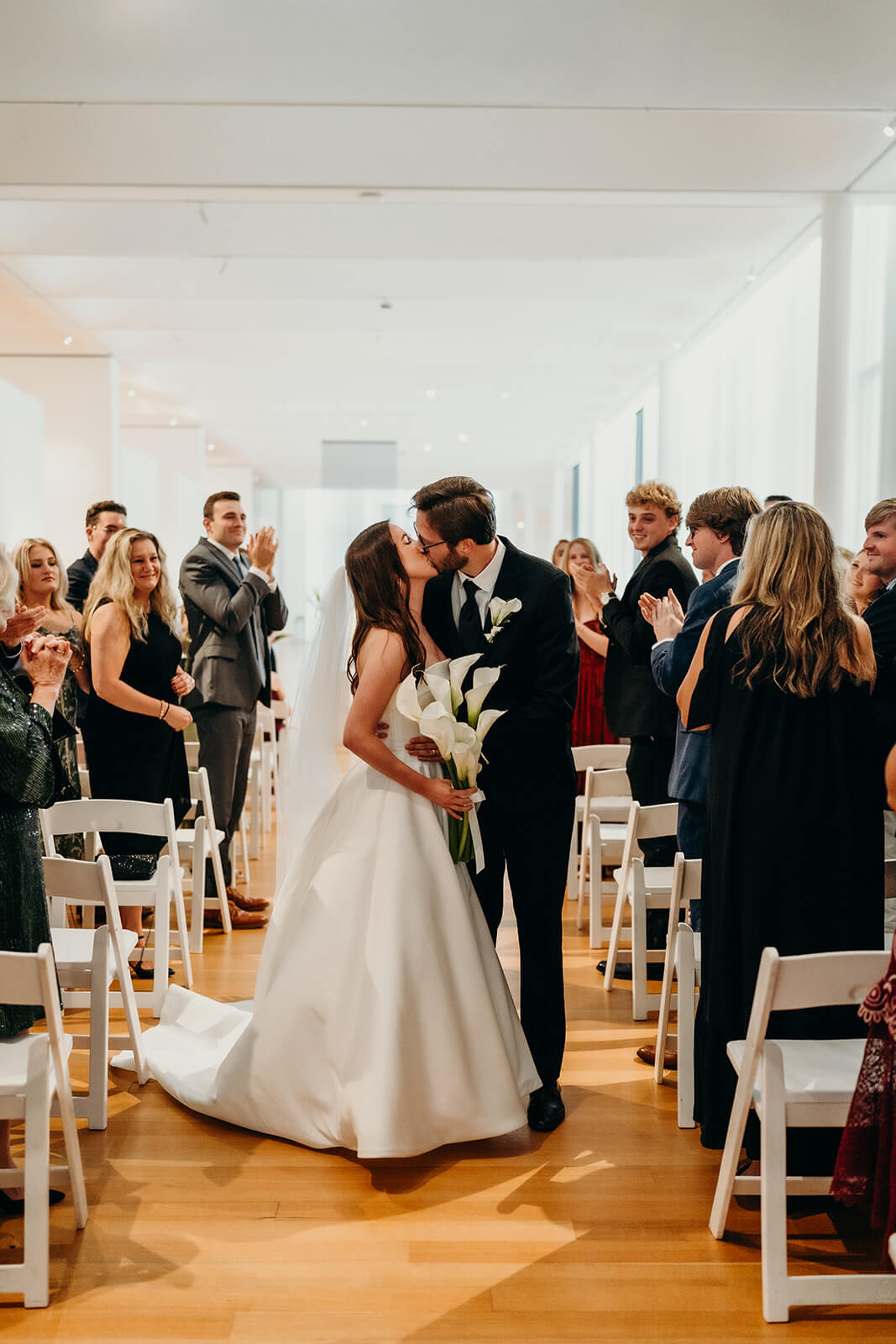 bride and groom walking back down the aisle after the ceremony and kissing as guests cheer