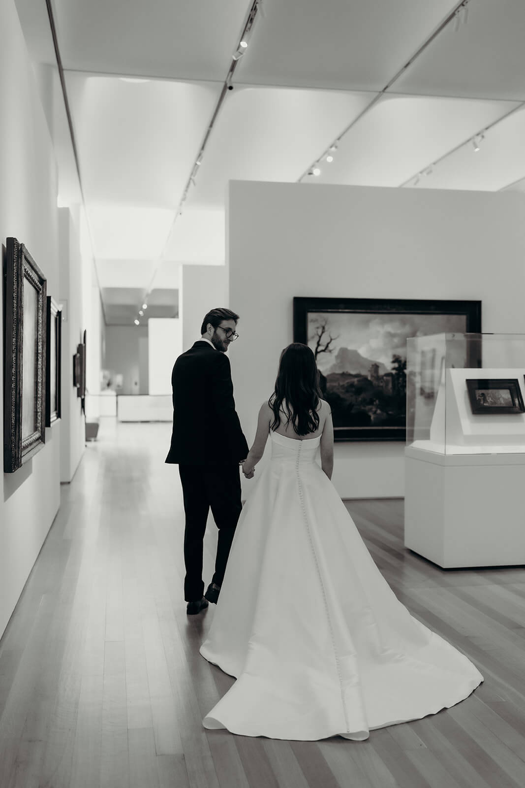 Bride and groom wedding portraits kissing in front of the indoor art gallery oil paintings NCMA wedding photos