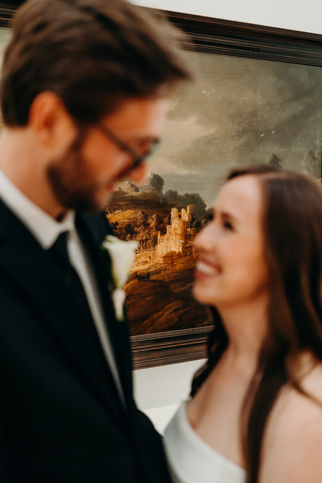 Bride and groom wedding portraits kissing in front of the indoor art gallery oil paintings NCMA wedding photos