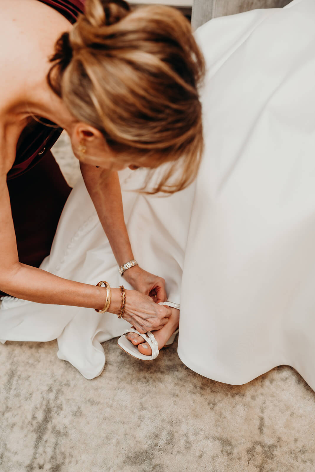 bride getting ready while mom helps her into her dress and shoes